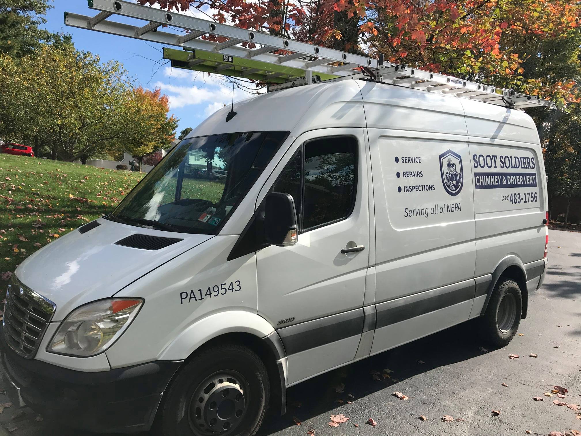 Soot Soldiers service van with ladder rack parked in a neighborhood.